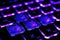 Gaming laptop keyboard with vivid purple-blue backlight. Neon glow stylization
