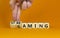 Gaming and streaming symbol. Businessman turns wooden cubes and changes the word gaming to streaming. Beautiful orange table