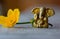 Ganesha figure with bright yellow flower closeup. Beautiful Ganesh statue with open palm and blooming flower on wooden board.