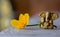 Ganesha figure with bright yellow flower closeup. Beautiful Ganesh statue with open palm and blooming flower on wooden board.