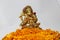 Ganesha made from brass with foreground yellow marigold flower and white background.