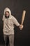 Gangster guy threaten with bat weapon. Bearded man hold baseball bat. Hooligan wear hood in hoodie tshirt. Aggression or