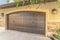 Garage door with an arched design against the concrete and brick wall of a home