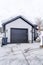 Garage of home with snowy gable roof and dark gray door against cloudy sky view