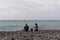 Garajau - Family with small child sitting on idyllic volcanic black stone beach of Praia Garajai, Canico, Madeira island, Portugal