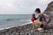 Garajau - Mother holding daughter on idyllic volcanic black stone beach of Praia Garajai, Canico, Madeira island, Portugal