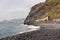 Garajau - Mother holding daughter on idyllic volcanic black stone beach of Praia Garajai, Canico, Madeira island, Portugal