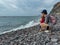 Garajau - Mother holding daughter on idyllic volcanic black stone beach of Praia Garajai, Canico, Madeira island, Portugal