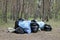 Garbage bags filled with waste among the trees in the forest. Environmental pollution by household waste. Plastic bags
