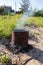 Garbage burns in an old barrel in the garden on a summer day. Smoke, danger, environmental concept.