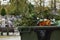 A garbage can in the cemetery with visible branches and artificial flowers