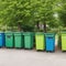 Garbage cans for separate sorting of garbage against the background of green trees