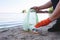 Garbage collection on the beach. Plastic and packages scattered on the beach. A man collects plastic. Ecology protection concept