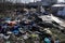 Garbage and construction debris scattered all around an empty lot in Bucharest, near a makeshift shelter