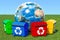 Garbage containers around Earth Globe in green grass against blu