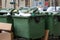 garbage-filled green tanks on wheels in the courtyard of a residential building