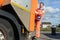 Garbage removal worker riding on the back of the disposal vehicle