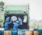 Garbage transportation workers. Scavengers take bins. Men load a metal container with garbage into a car for collecting and