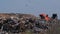 A garbage truck pours garbage out of its body at a landfill