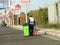 a garbageman worker in protective clothing walking with a dustbin collecting garbage for trash removal