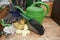 Garden accessories, watering can, hand scoop and protective gloves on rustic wooden background. Close-up.