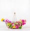 Garden basket with beautiful various colorful garden flowers at white wooden background, front view. Summer gardening