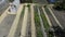 Garden beds top view. A woman removes a metal barrel from the site. Vegetable long and even beds and greenhouses at their summer