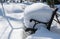 Garden bench covered with white fluffy snow after night snowfall. Calm picture of winter snow-covered garden.