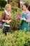 Garden center worker selling potted flower customer