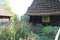 Garden by the country house made of wood and with a thatched roof, fenced off with a wooden fence