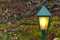 Garden decoration lamp post yellow illumination nature scenic environment with colorful green and brown colors blurred background