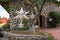 Garden decoration, silver stars adorning tree outside stone house