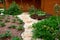 Garden Design. Pathway in garden, Flowers with bricks pathways. The care of garden plants