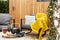 Garden with grey armchairs, yellow blanket and kettle and glass on the table