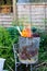 A garden incinerator bin rested on a metal chair frame burning scrap wood