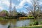 Garden lake pond with small island of plants surrounded by trees blue sky