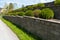 Garden landscape design. Decorative wall made of dark gray stone blocks or concrete cement bricks. Garden decorative trimmed