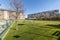 A garden with a lot of grass, tropical umbrellas and a swimming pool in a common area of an urbanization of urban residential