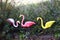 Garden ornamental flamingo birds against the wire fence