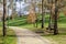 Garden or park bench near an empty dirt path, track, trail or pathway through the trees and green grass lawn