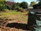 A garden with piles of leaves raked up, and a bin