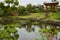 Garden with pond, rocky steps, trees, grass, flowers, and traditional gazebo in Camillia Hill of Jeju Island, South Korea