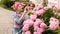 Garden scene with woman plants hydrangea, watering flowers in backyard, spring time.