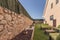 Garden of a single-family home with a metal fence and stone ashlar, floors covered with artificial grass and green pallet sofas