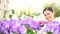 Garden springtime, woman florist smiling with white wicker basket flowers of purple primroses