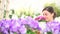 Garden springtime, woman florist smiling with white wicker basket flowers of purple primroses