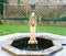 Garden water fountain with eagle symbol and other figure heads .
