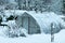 garden in winter, greenhouse covered with snow, trees, garden house and garden accessories