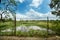 Garden wire fences and lake and sky at the back