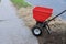 Garden worker with sowing lawn grass seeds with a drop lawn spreader in the residential backyard